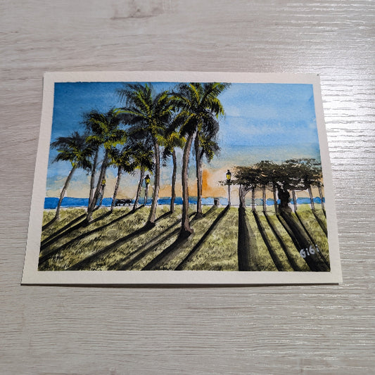Artistic depiction of palm trees on a postcard with a scenic background.